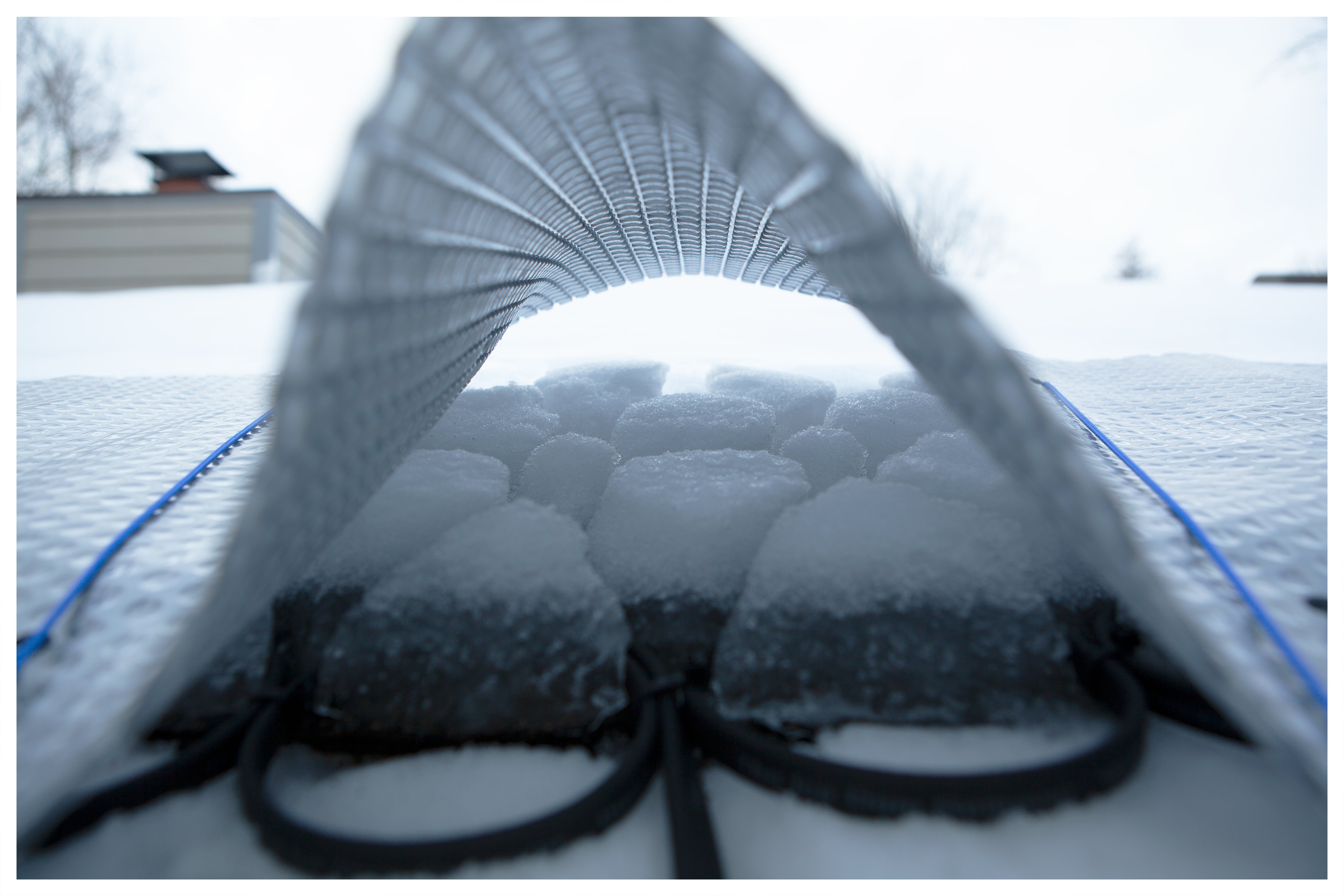 Peaking under the solar blanket to reveal The Ice Dam Remover melting an ice dam.